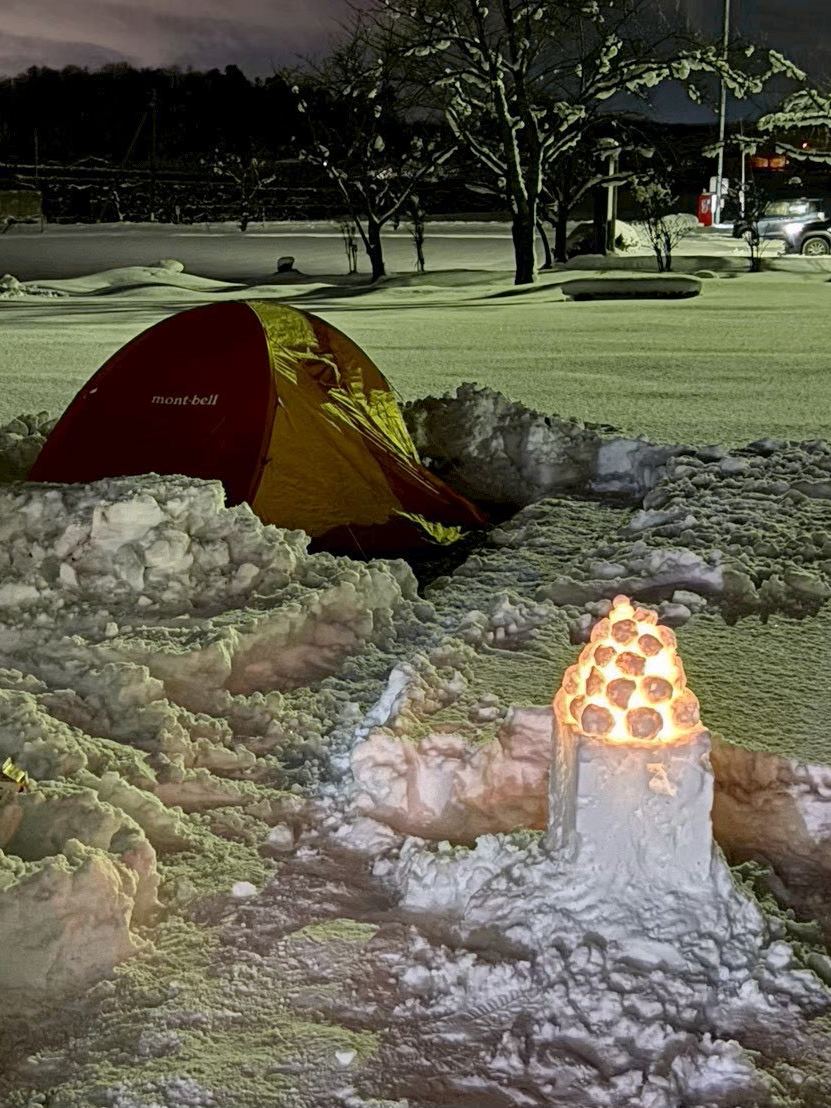 夜の雪原に灯る雪灯篭とテント